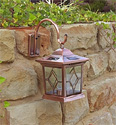 Picture of a hanging copper solar light mounted to the side of a rock wall.